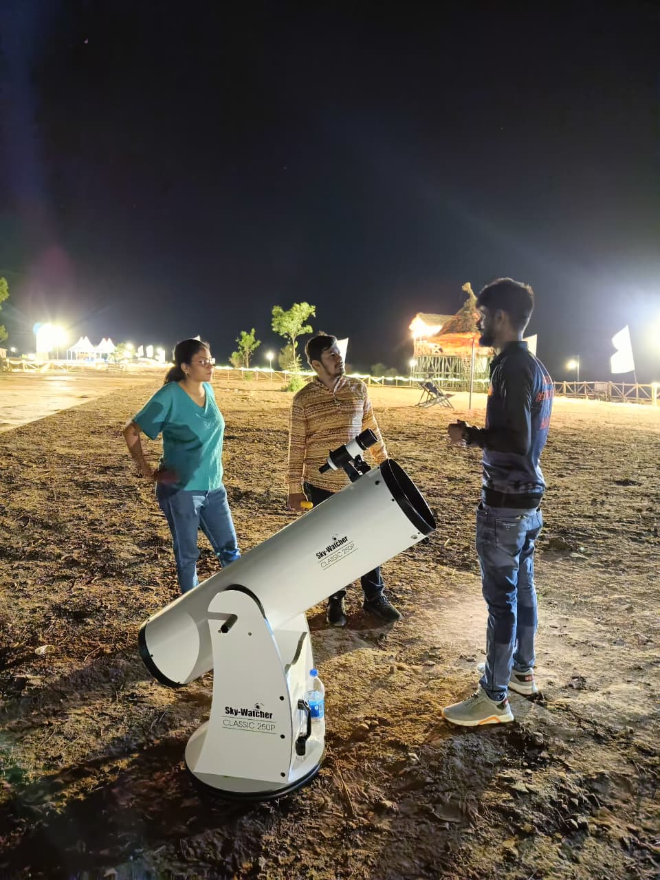 A guide showing tourists the night sky through a telescope